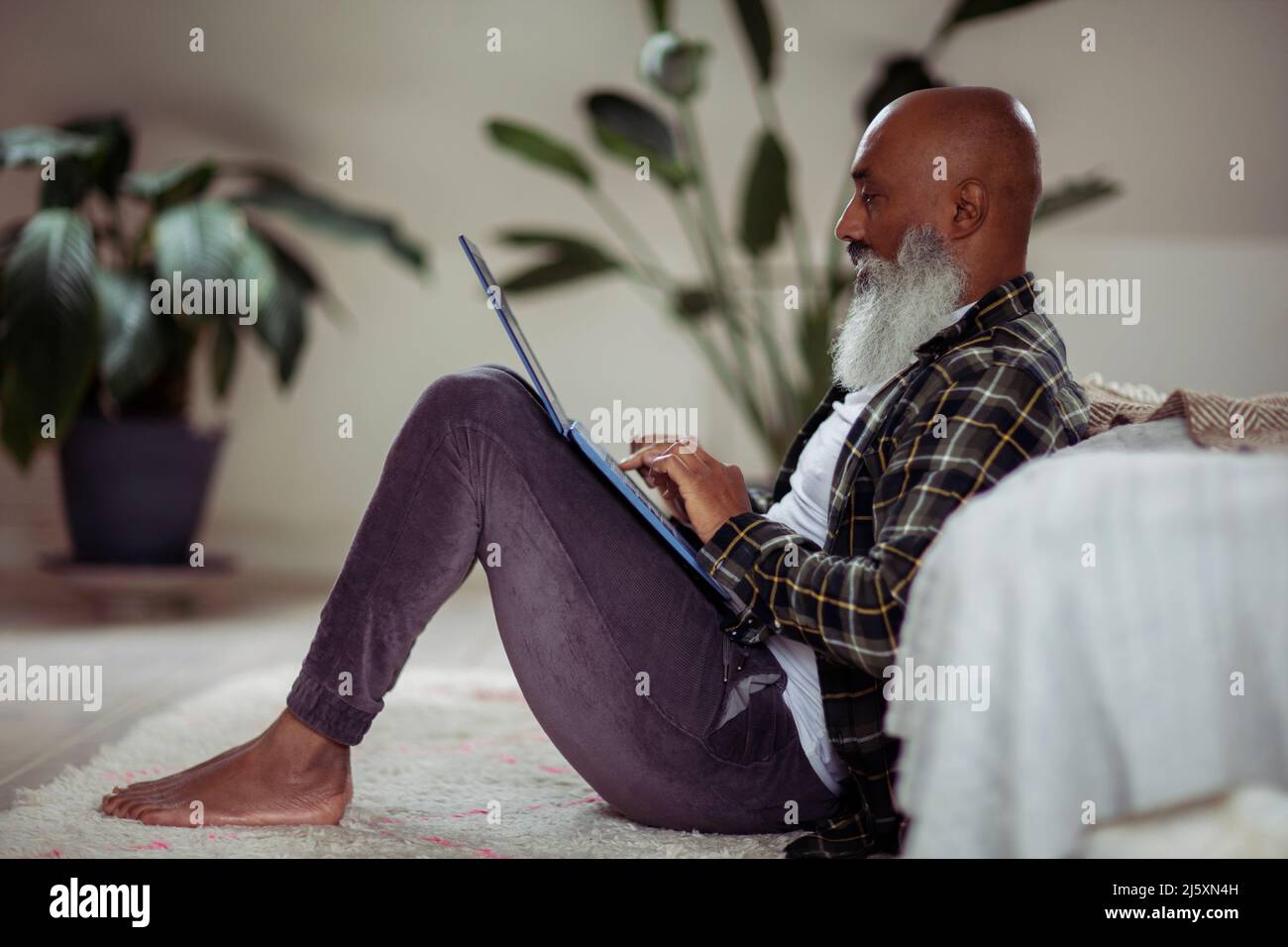 Mature man with beard using laptop on floor Stock Photo