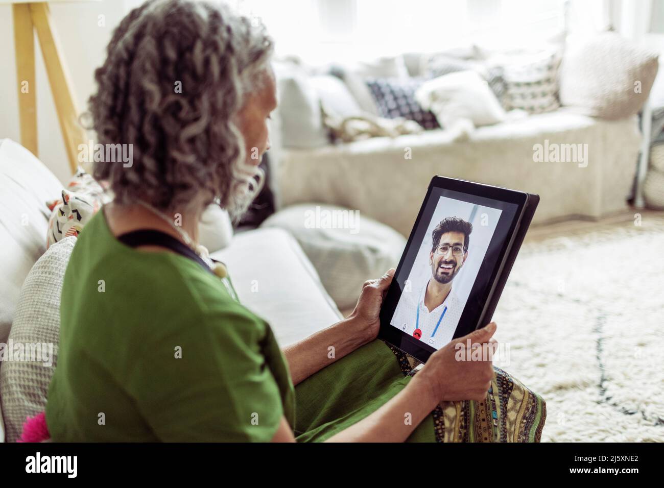Senior woman video chatting with doctor on digital tablet screen Stock Photo