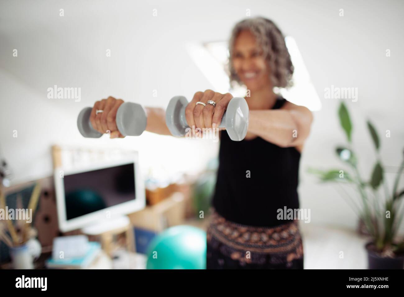 Senior woman exercising with dumbbells at home Stock Photo
