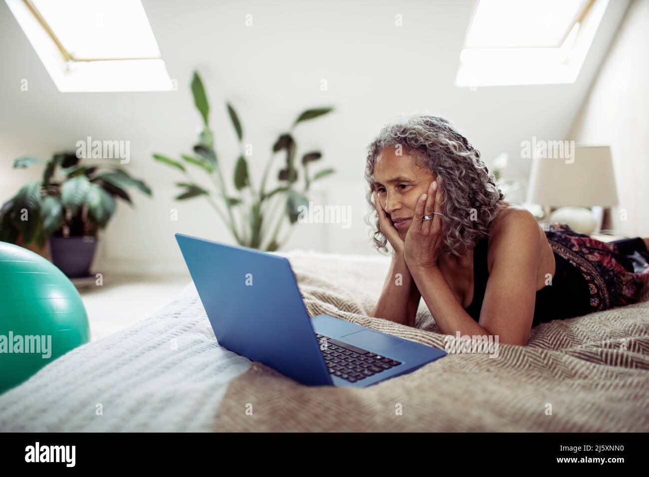 Senior woman using laptop on bed Stock Photo