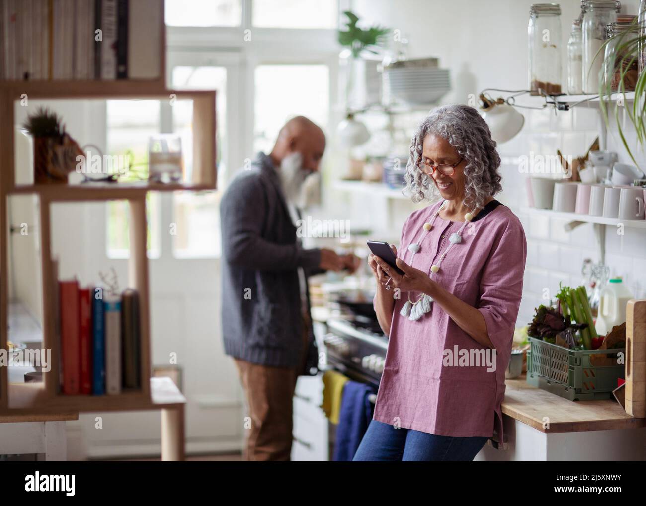Senior woman using smart phone in kitchen Stock Photo