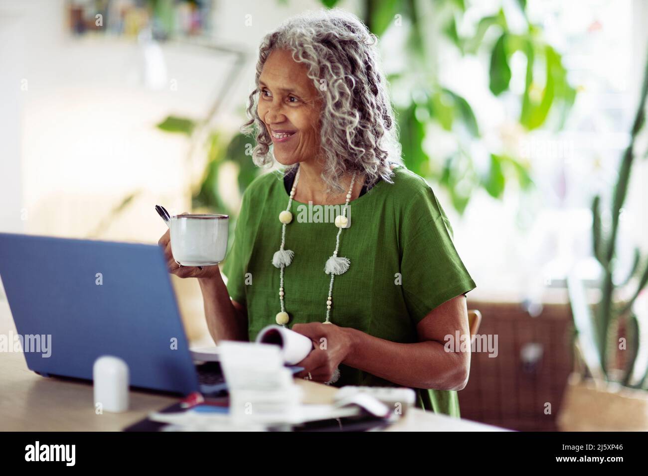Happy senior woman drinking tea at computer Stock Photo