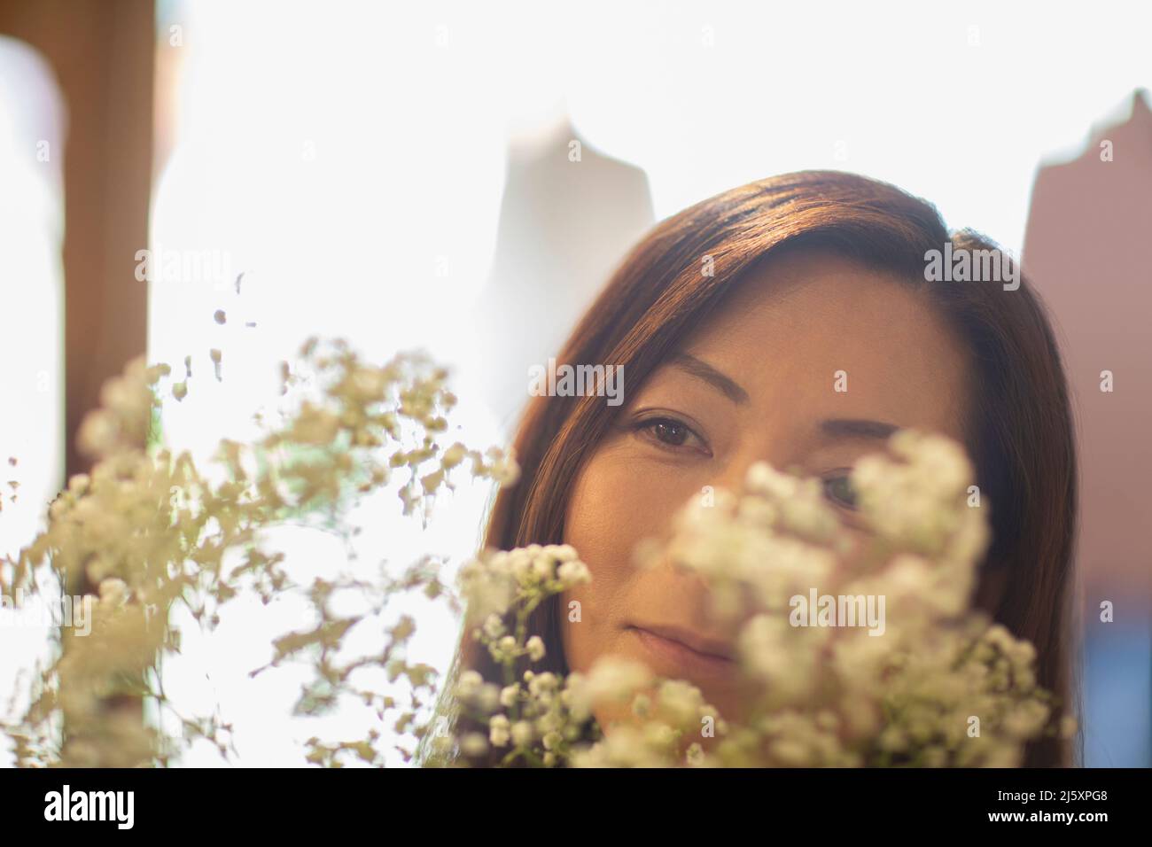 Close up woman looking at white flowers Stock Photo