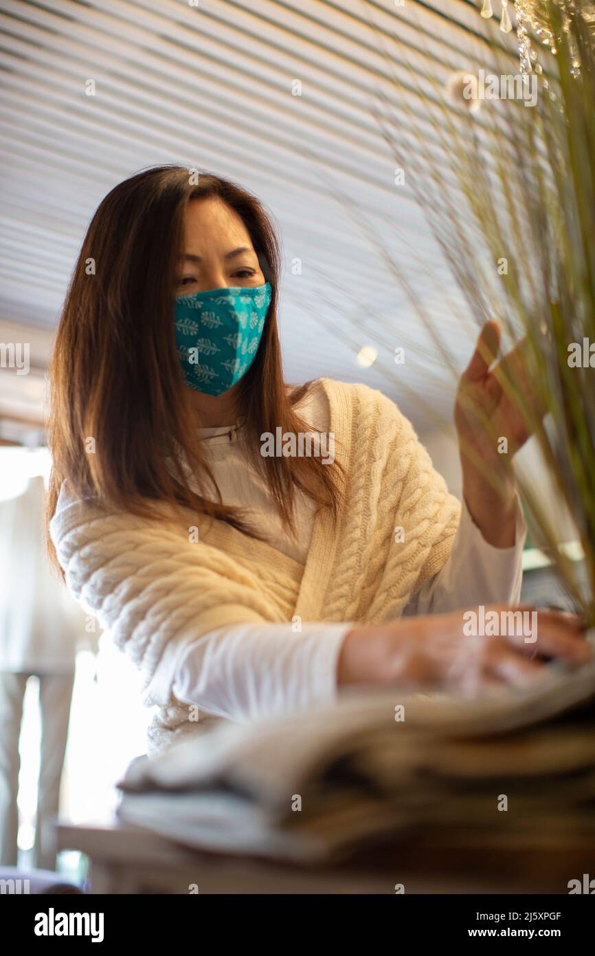 Female shop owner in face mask arranging display Stock Photo
