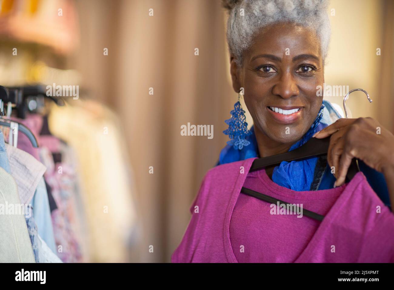 Portrait happy confident senior woman shopping in clothing shop Stock Photo