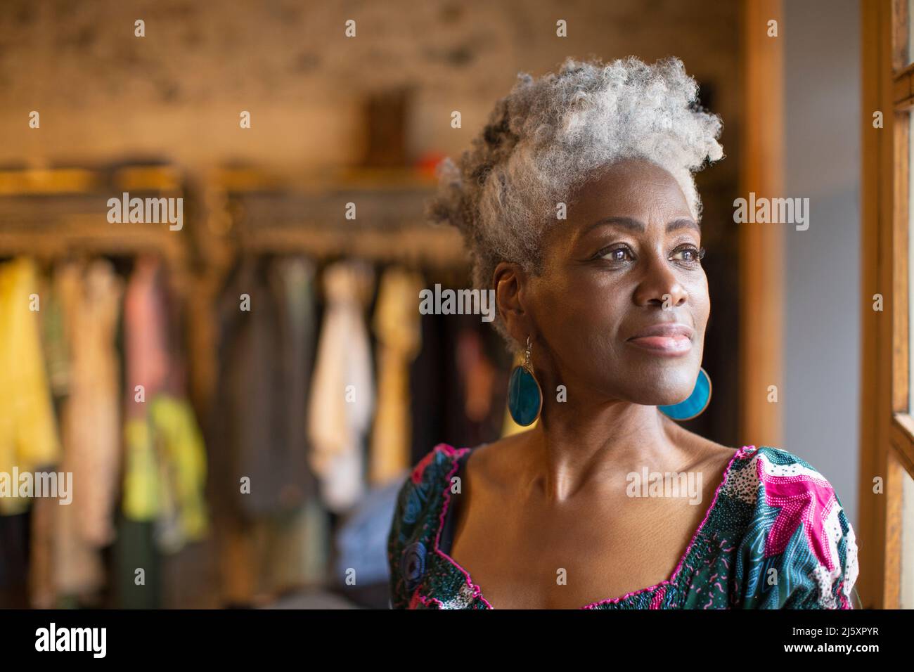 Portrait thoughtful senior female shop owner looking out window Stock Photo