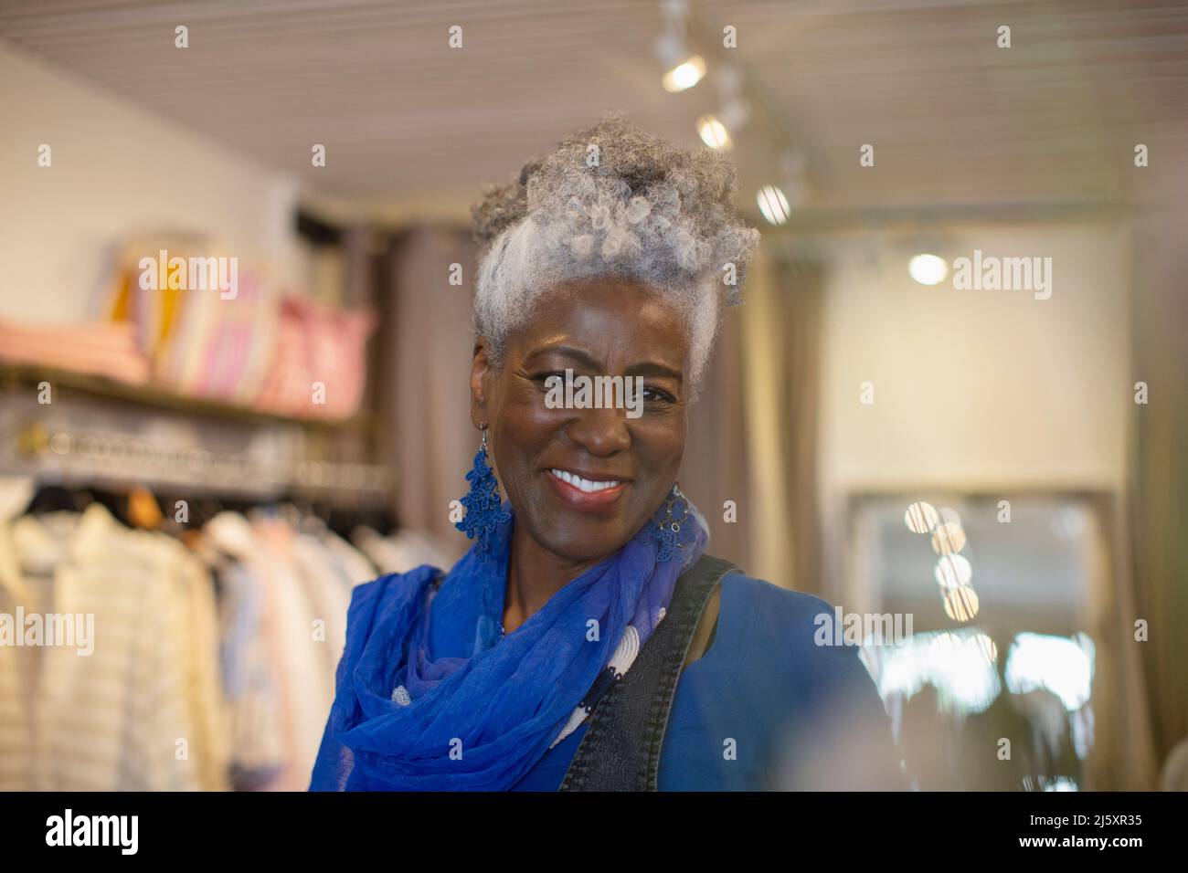 Portrait confident beautiful senior woman in clothing shop Stock Photo
