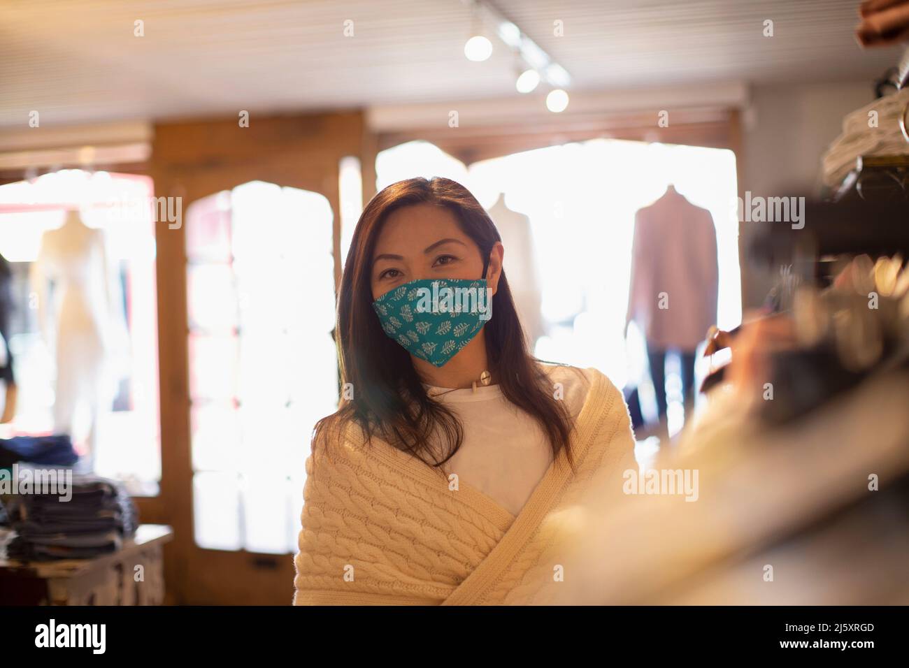 Portrait confident female shopper in face mask in clothing boutique Stock Photo