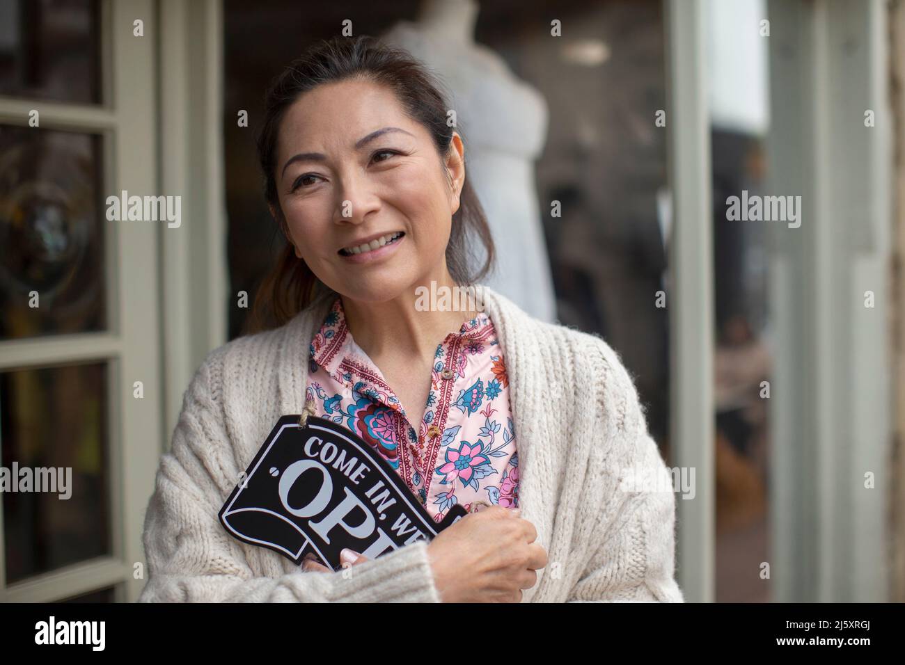 Smiling female shop owner holding open sign Stock Photo