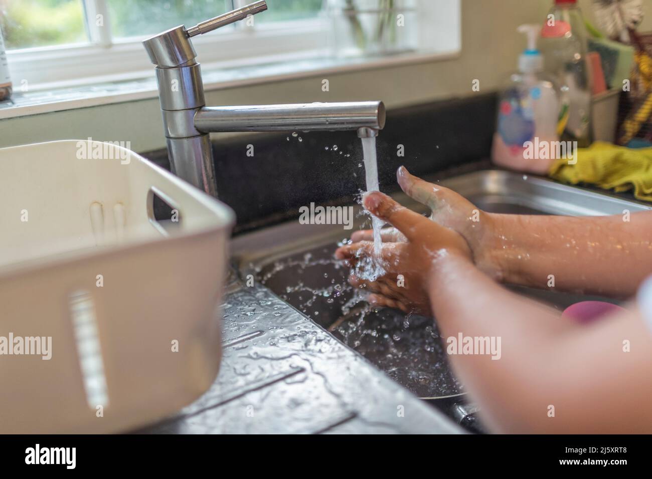 Close up boy washing hands at kitchen sink Stock Photo