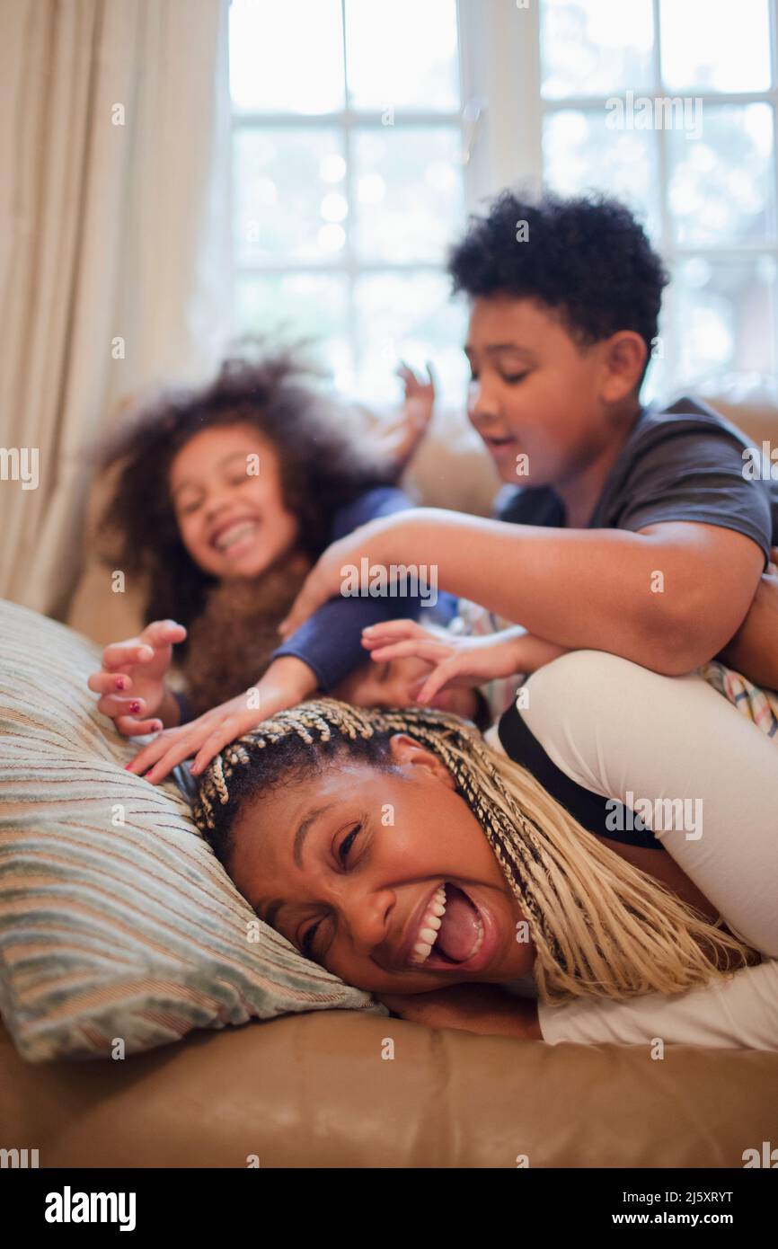 Playful mother and kids on sofa Stock Photo