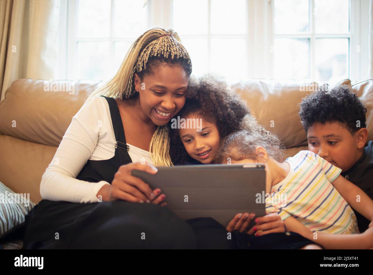 Happy mother and kids video chatting with digital tablet on sofa Stock Photo