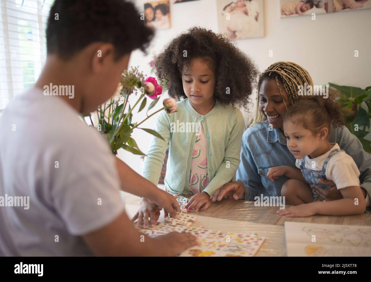 Mother and kids assembling puzzle at table Stock Photo