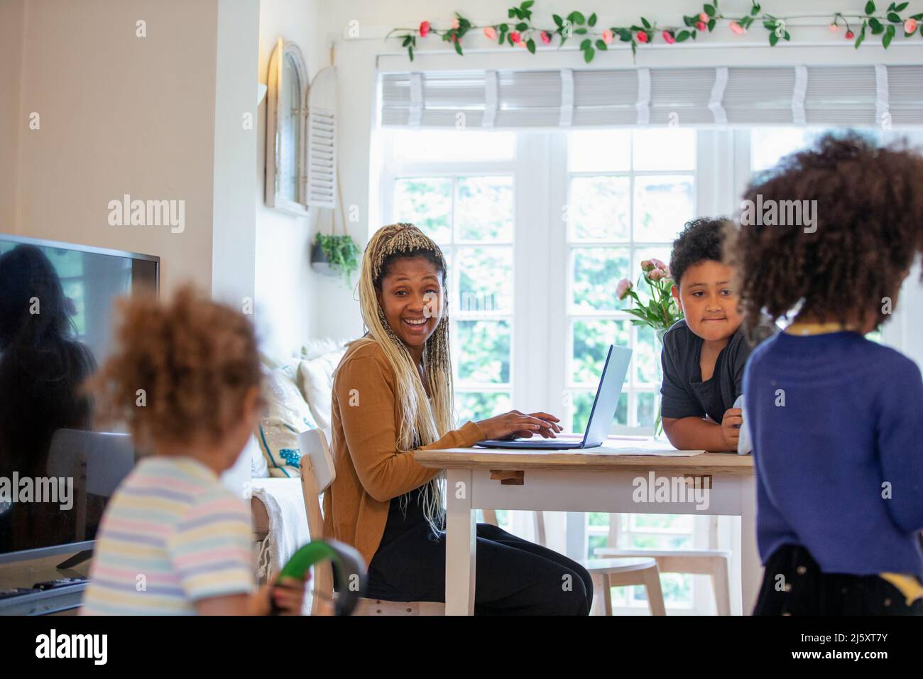 Happy mother working from home and watching kids play Stock Photo