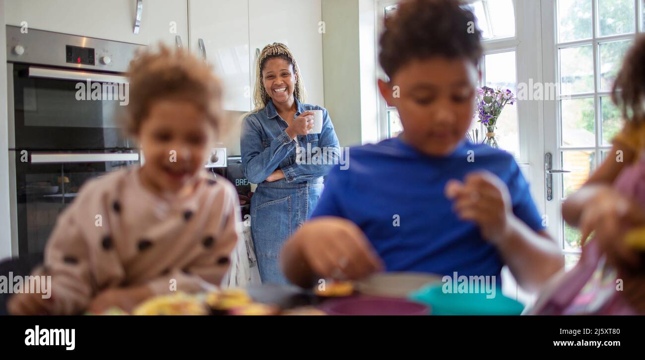 Happy mother watching kids bake in kitchen Stock Photo