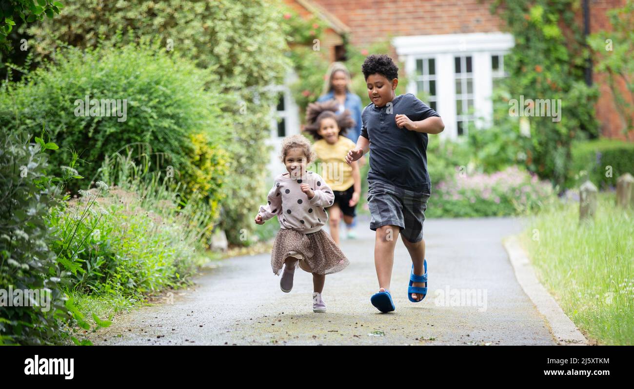 Happy brother and sister running in driveway Stock Photo - Alamy