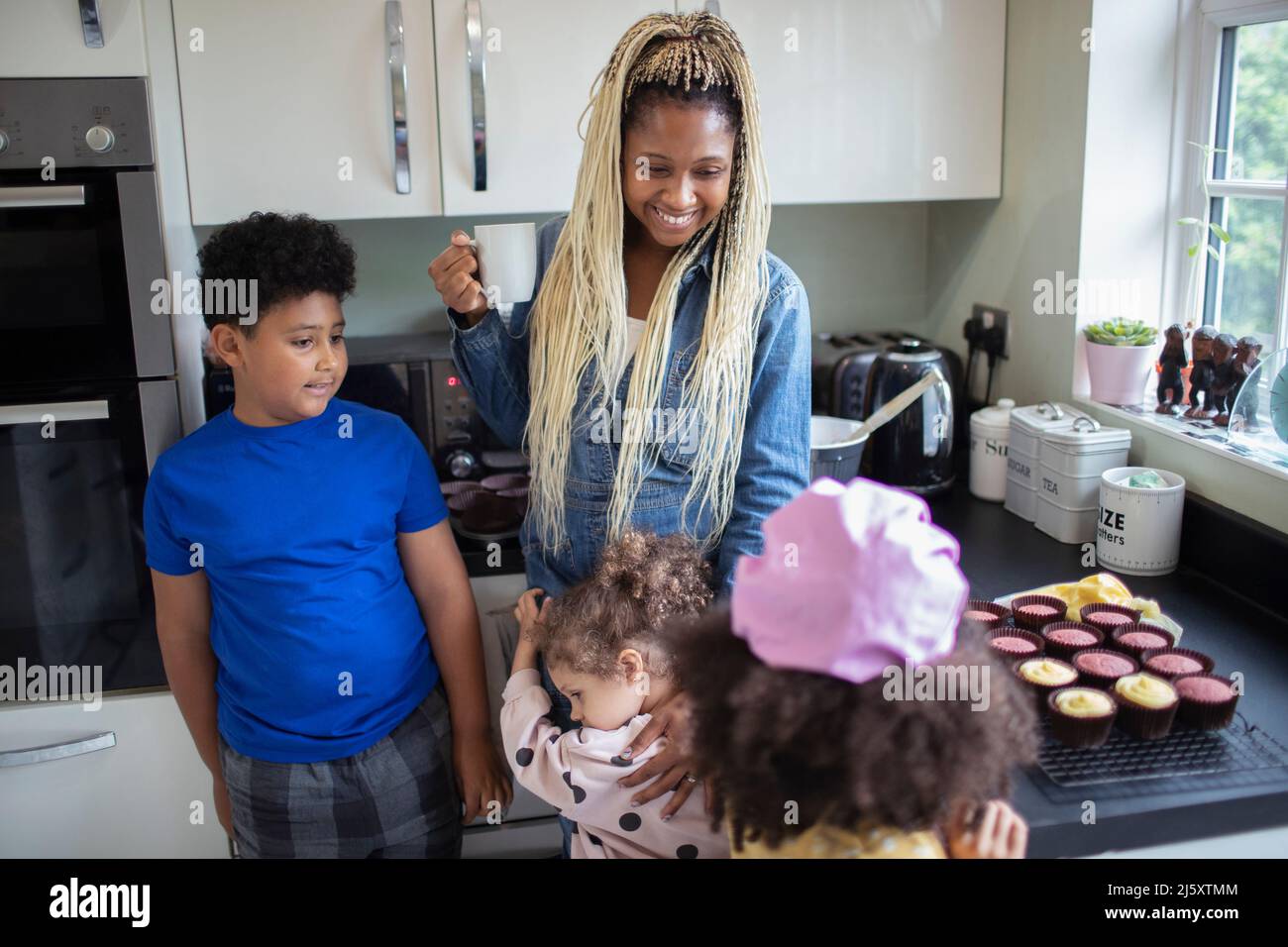 Happy mother and kids baking cupcakes in kitchen Stock Photo