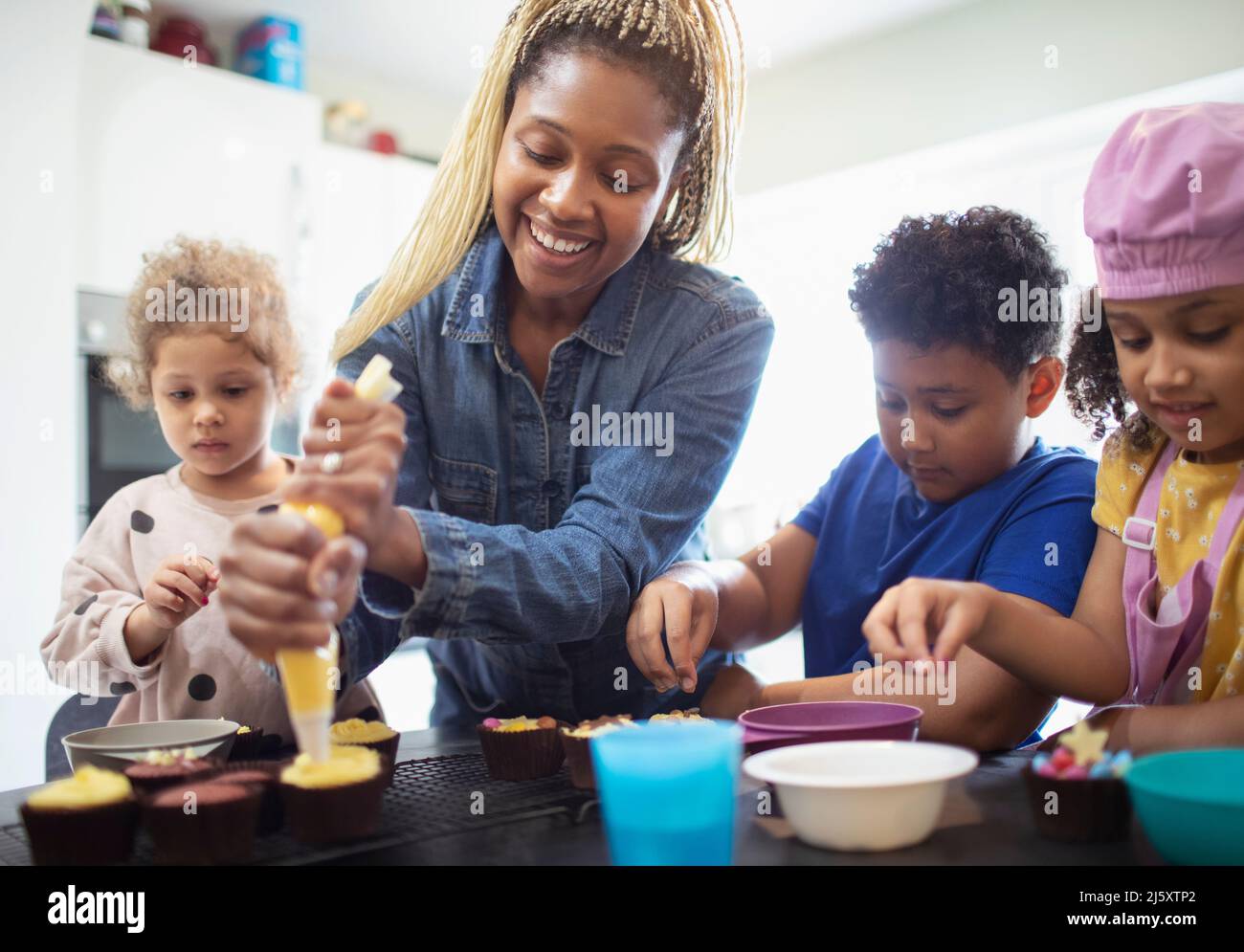 Happy mother and kids decorating cupcakes in kitchen Stock Photo