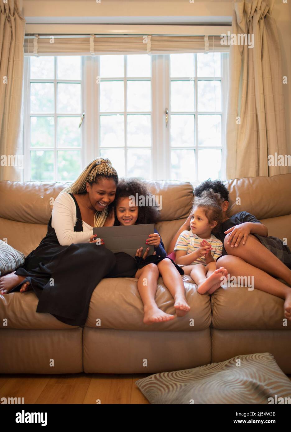 Mother and kids using digital tablet on living room sofa Stock Photo