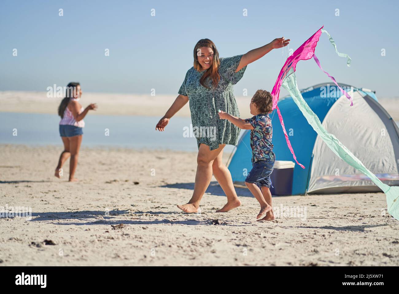 Happy mother and son playing with kite on sunny beach Stock Photo