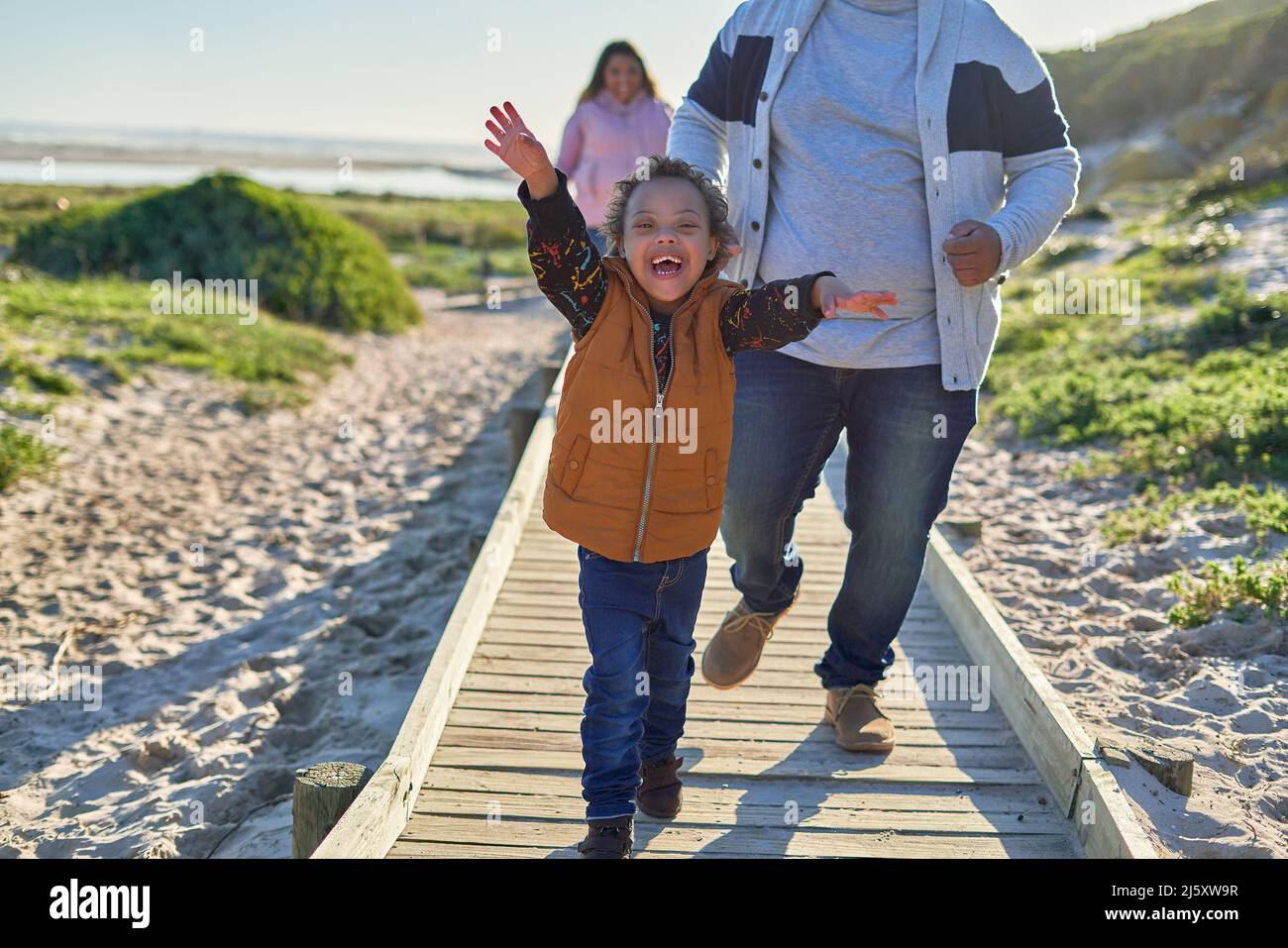 Happy, exuberant boy with Down Syndrome on beach boardwalk Stock Photo