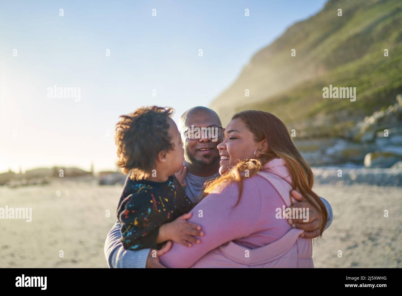Happy parents and son hugging on sunny beach Stock Photo