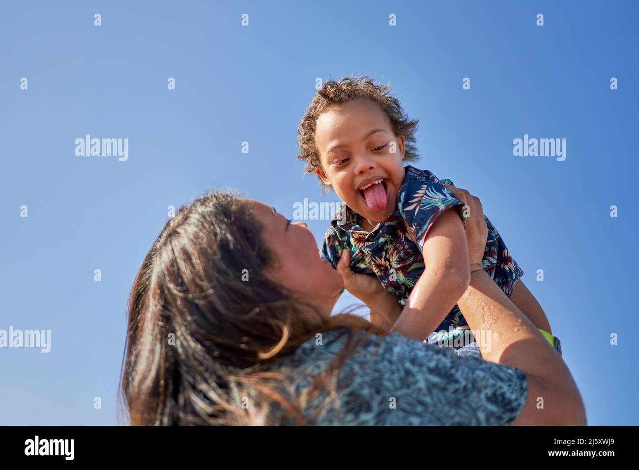 Mother lifting happy son with Down Syndrome Stock Photo