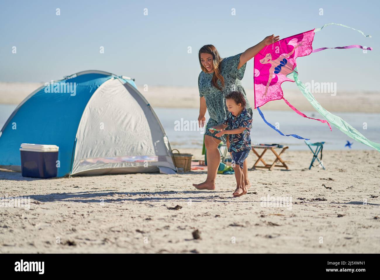 Happy mother and son with Down Syndrome playing with kite on beach Stock Photo