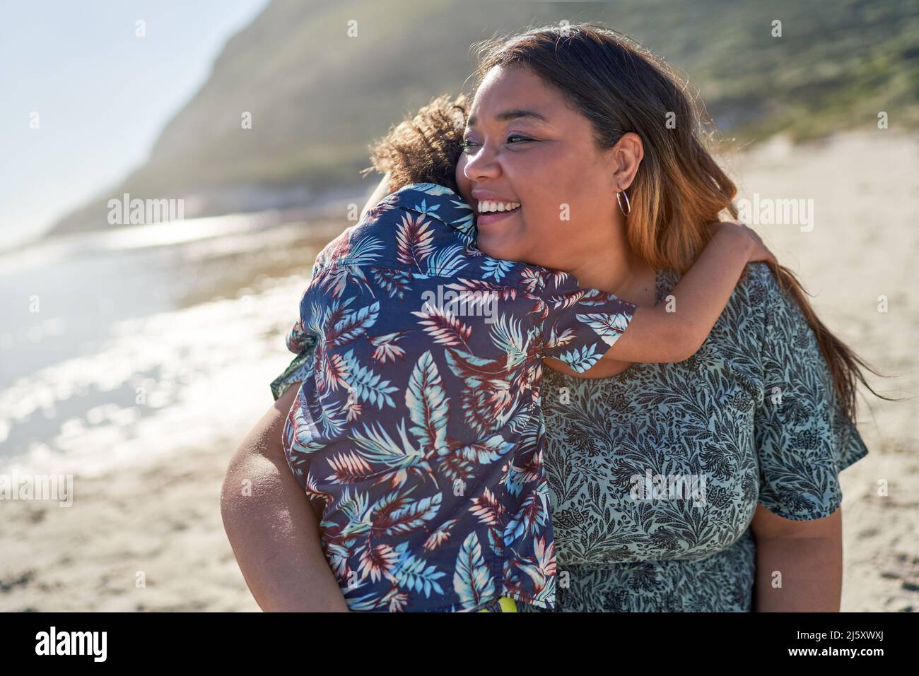 Happy mother hugging son on sunny beach Stock Photo