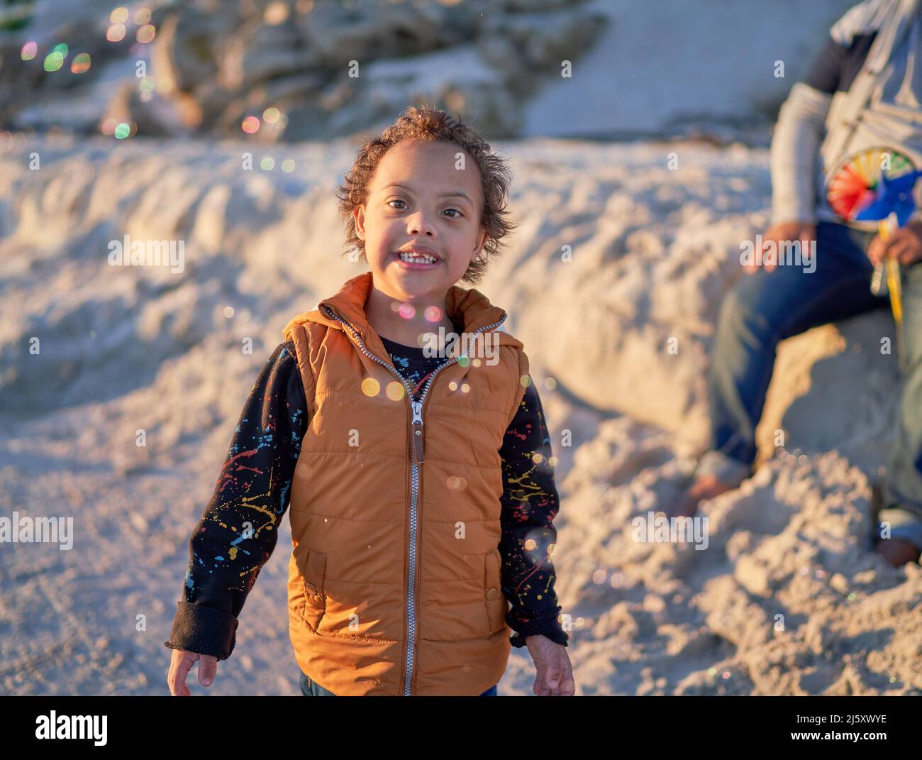 Portrait cute boy with Down Syndrome watching bubbles on beach Stock Photo