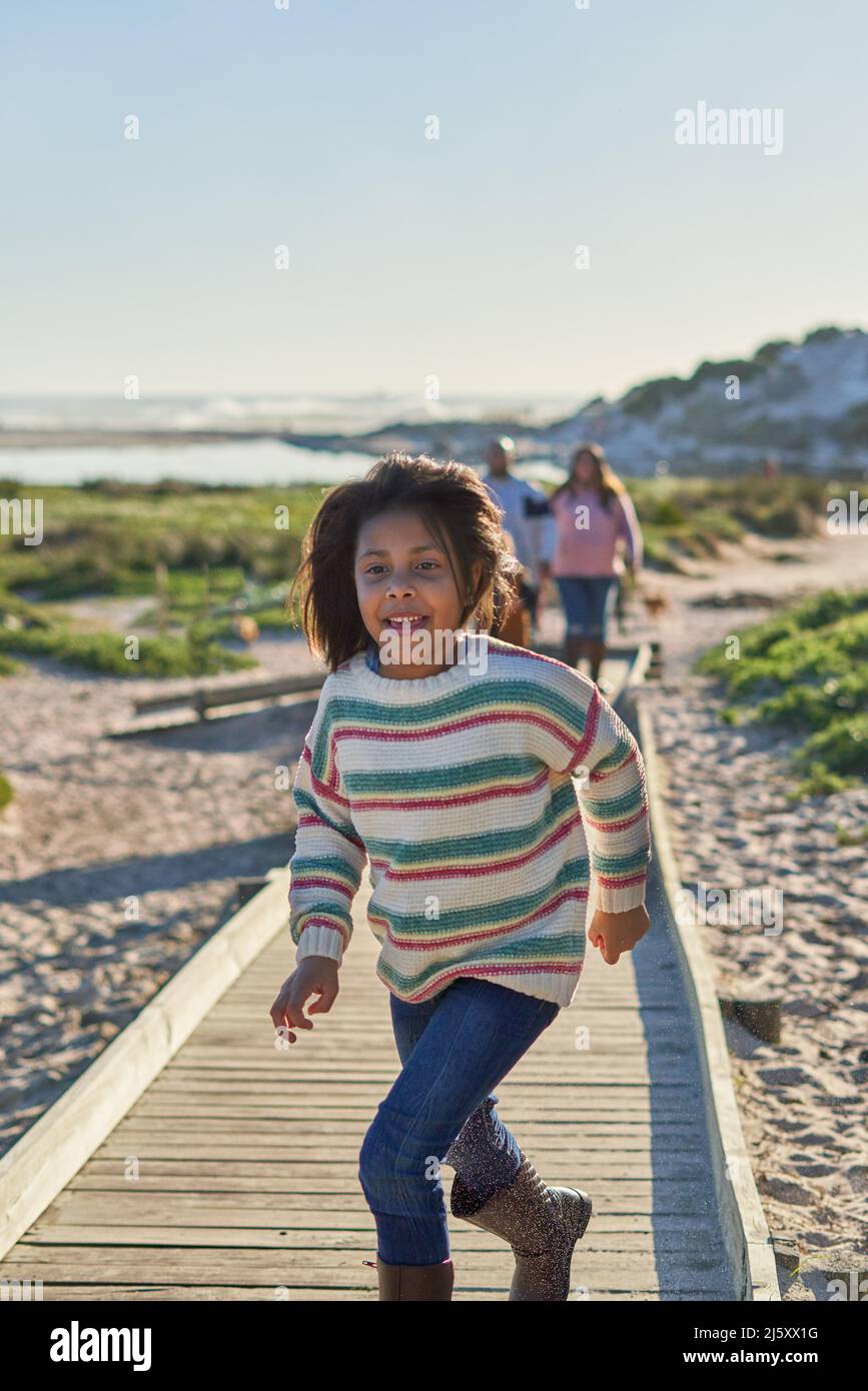 Carefree girl running on sunny beach boardwalk Stock Photo