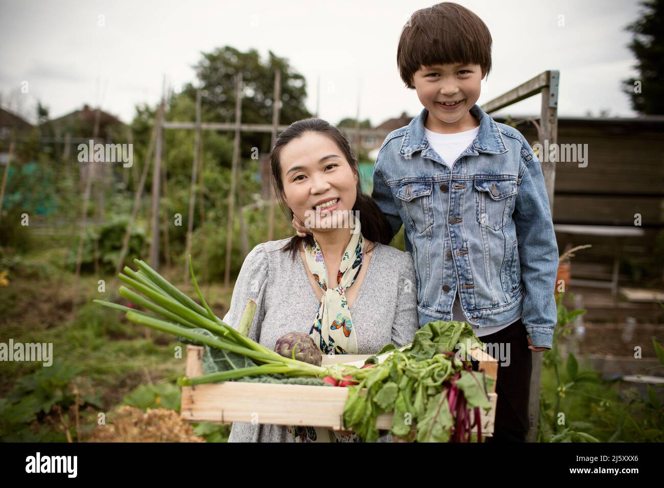 Portrait happy mother and son with harvested vegetables in garden Stock ...