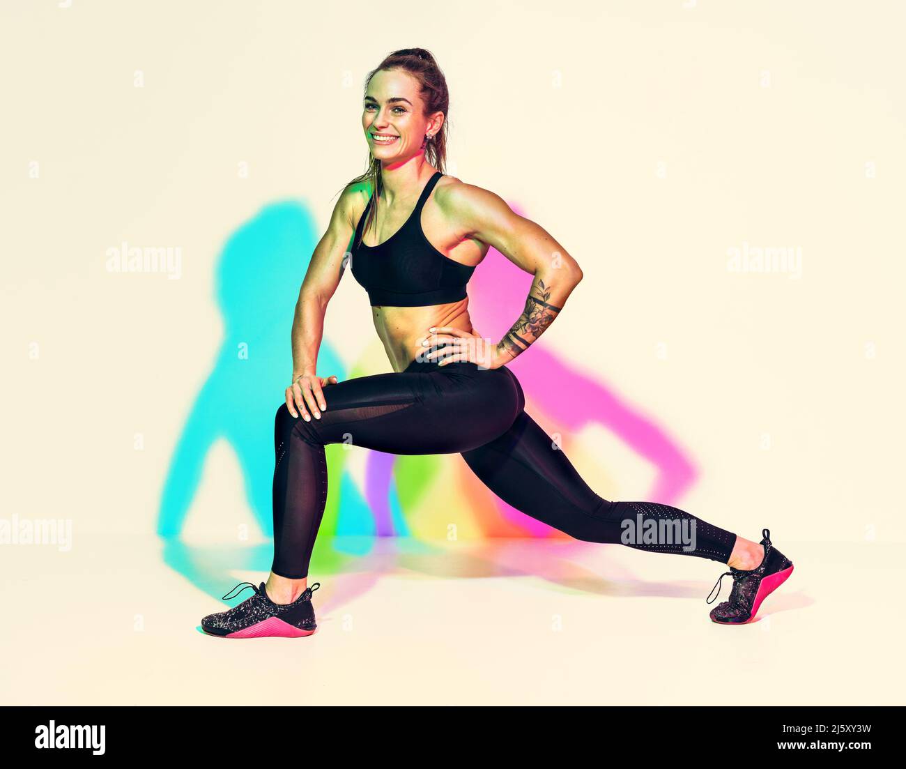 Warming up before training. Photo of laughing woman in black sportswear on white background with effect of rgb colors shadows. Sports motivation and h Stock Photo