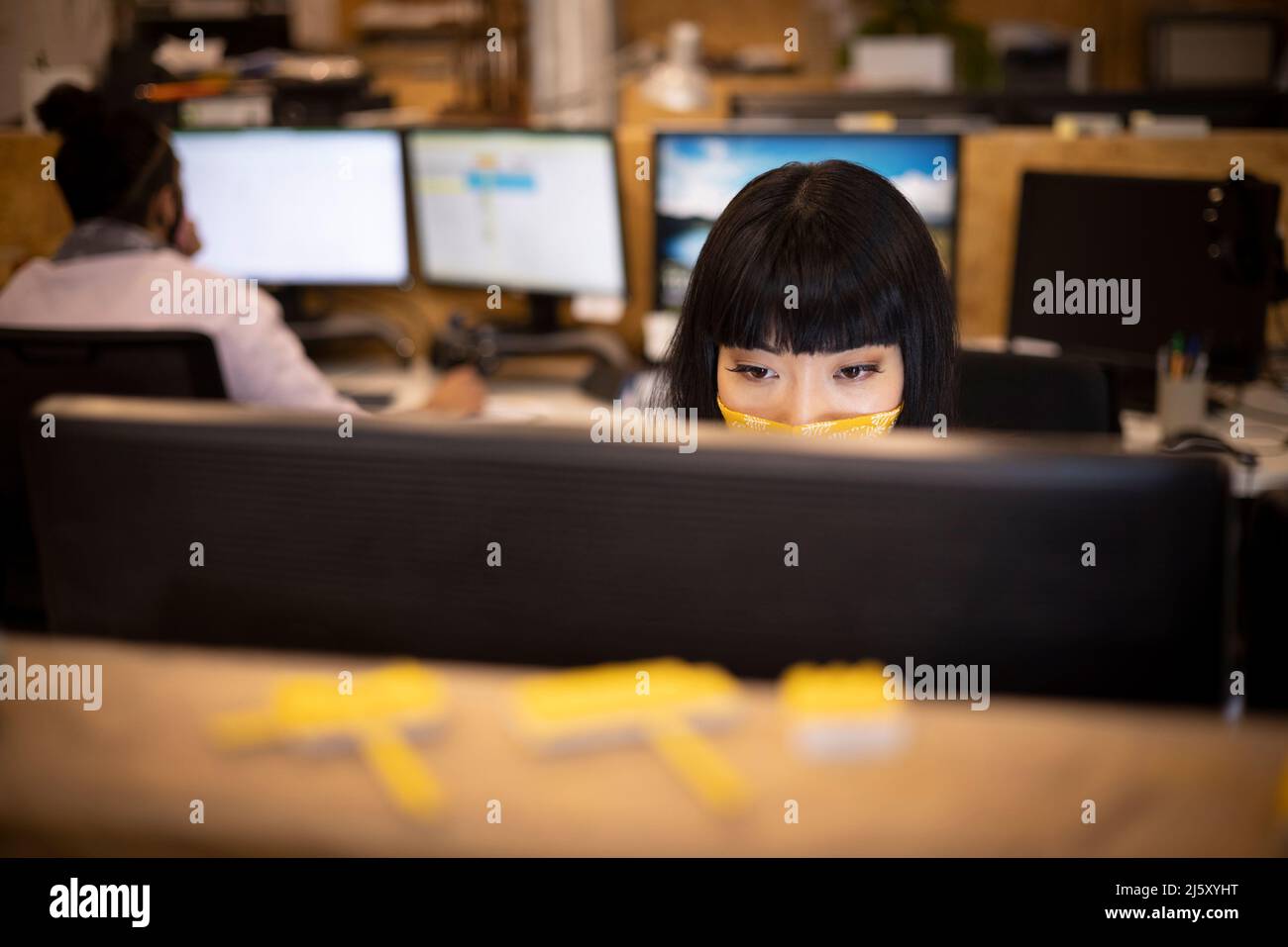 Businesswoman in face mask working at computer in office Stock Photo