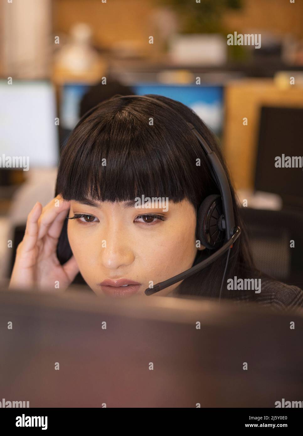 Close up serious businesswoman in headset working at computer Stock Photo