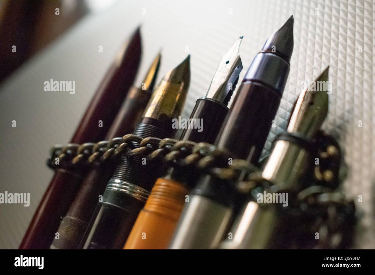 Few pens wrapped in an iron chain lies on table. Concept- restriction of freedom of speech. Stock Photo