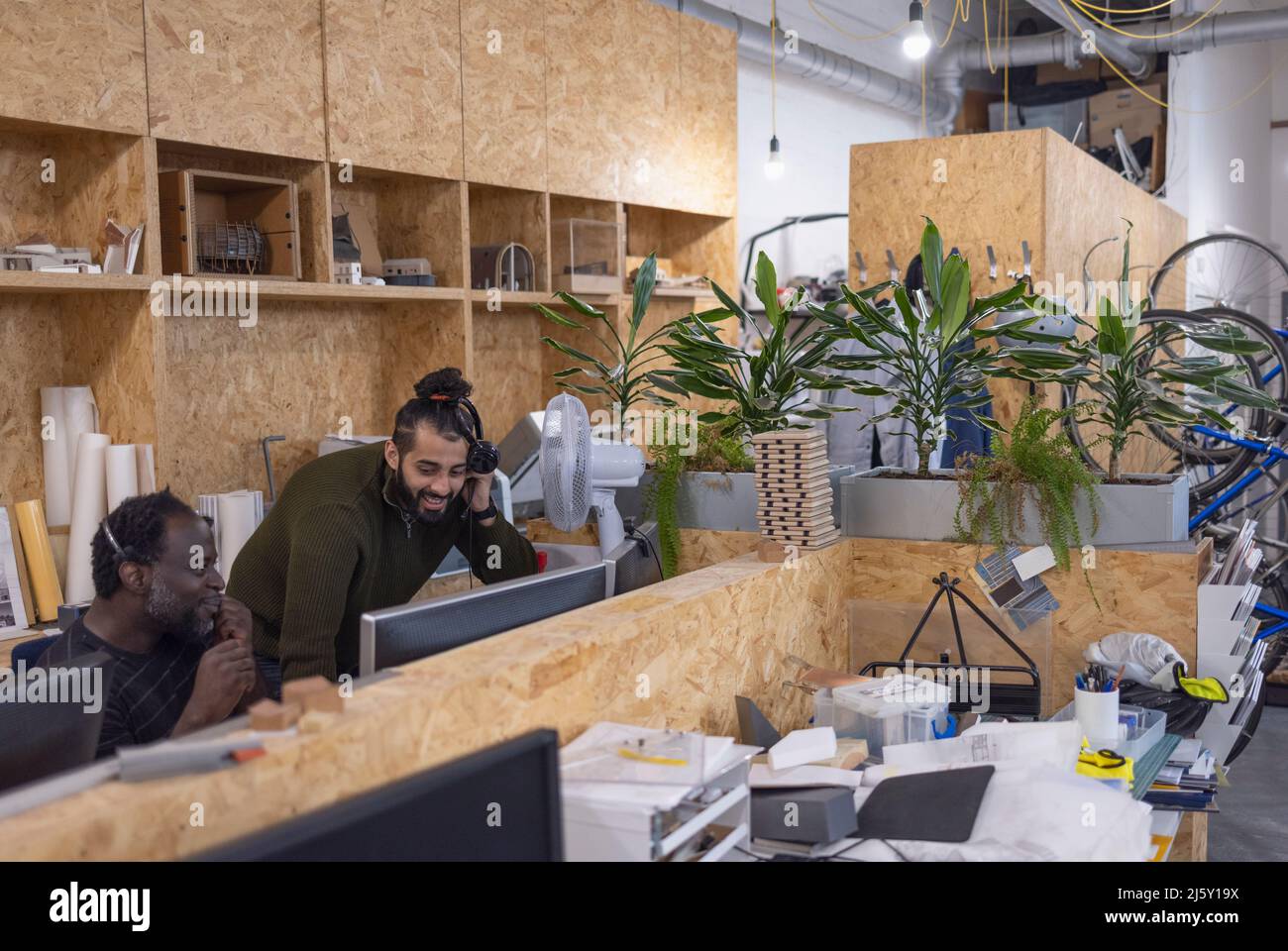 Businessmen with headphones working in open plan office Stock Photo