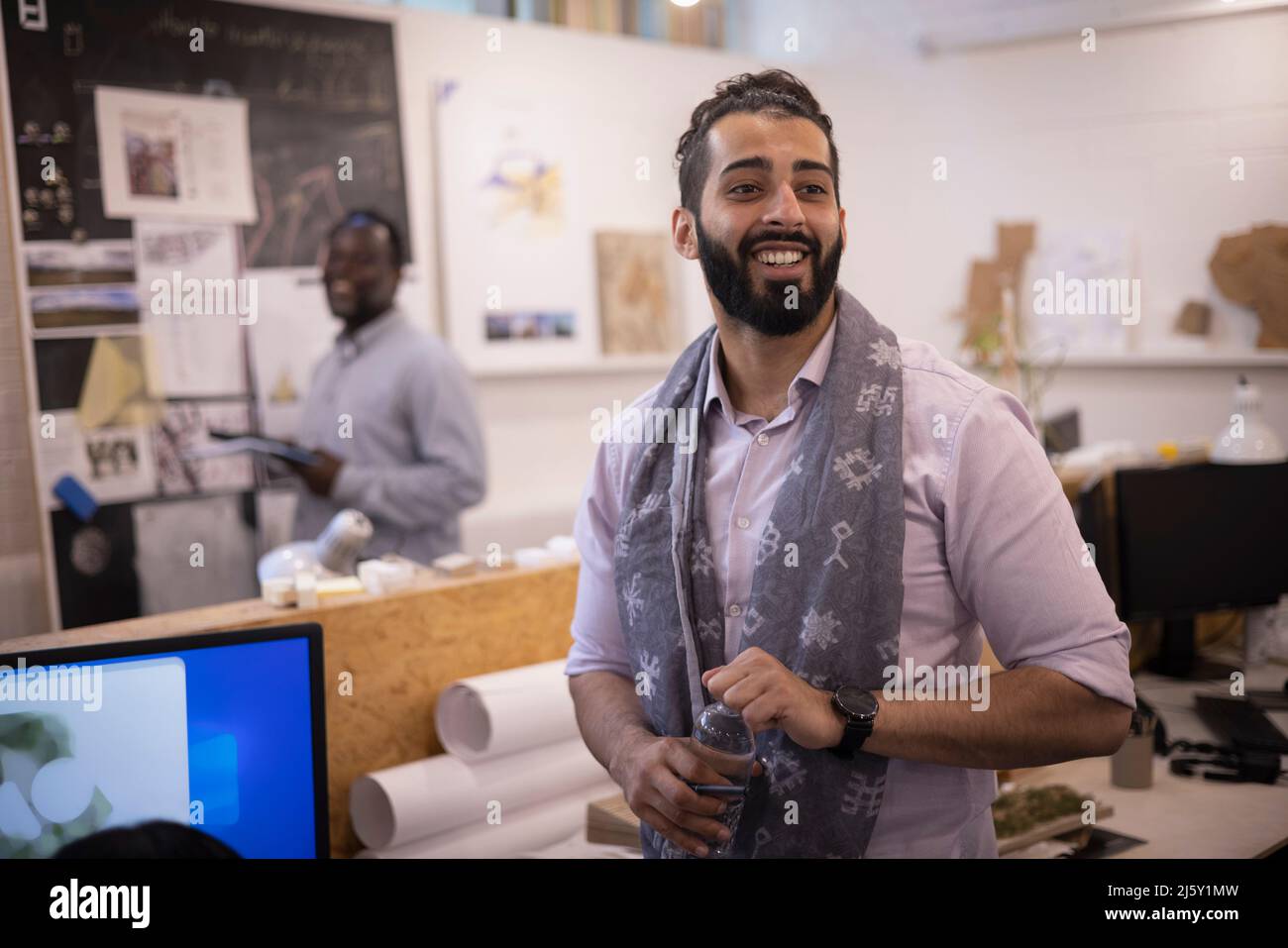 Smiling young businessman in scarf standing in office Stock Photo