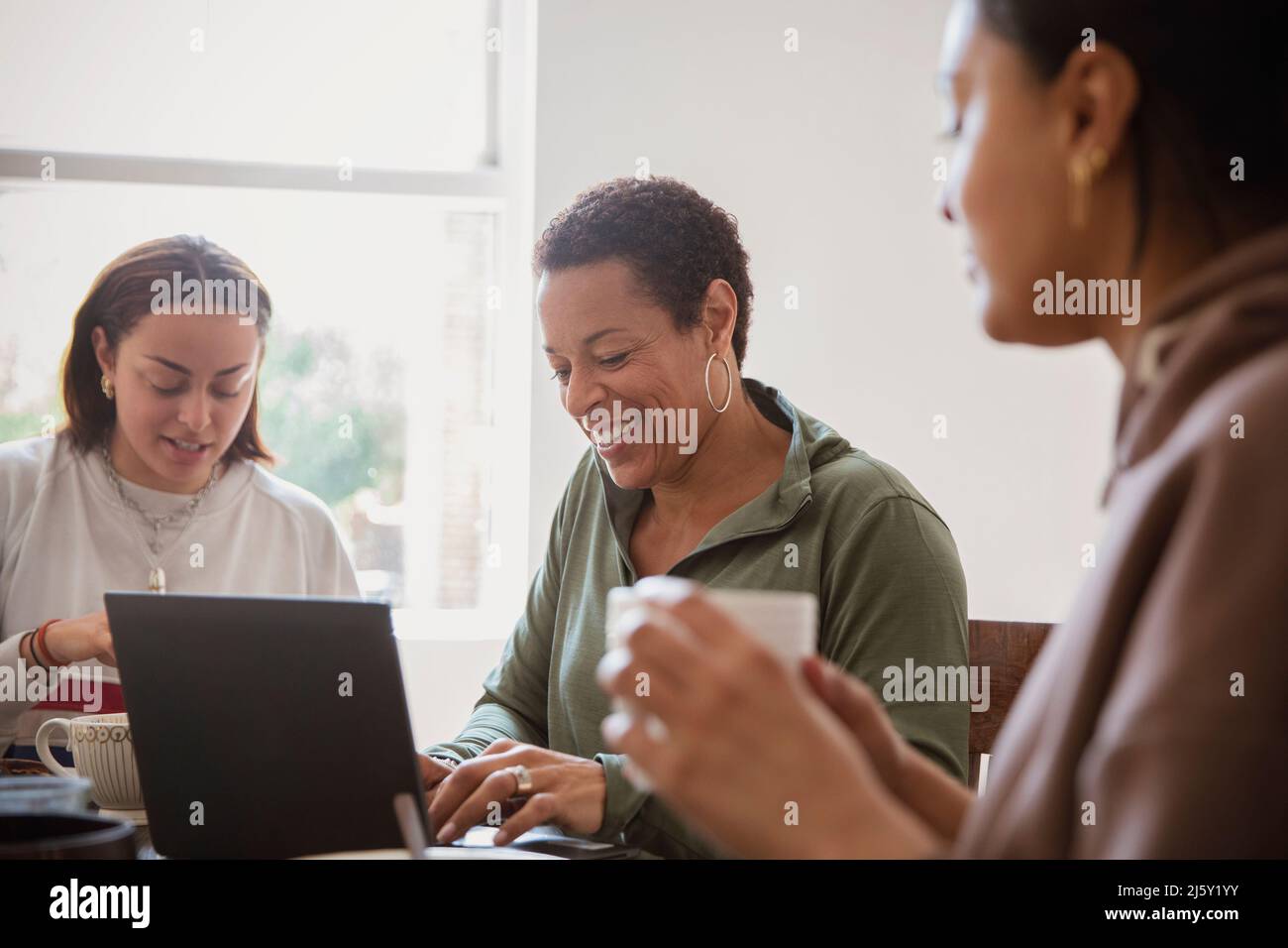 Happy woman working from home in dining room with daughters Stock Photo