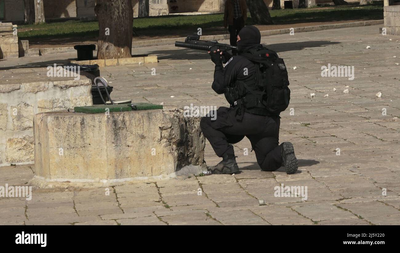 An Israeli policeman fires rubber-coated bullets at Palestinians barricading themselves inside Al-Aqsa Mosque and throwing stones at the police and a group of religious Jews visiting the Temple Mount known to Muslims as the Haram esh-Sharif (Noble Sanctuary) during the Jewish Pesach (Passover) holiday in the old city on April 20, 2022 in Jerusalem, Israel. Jews, Christians and Muslims celebrate this year's Passover, Easter and Ramadan in the same week which caused tension between Palestinians and Israelis specially in Jerusalem Stock Photo