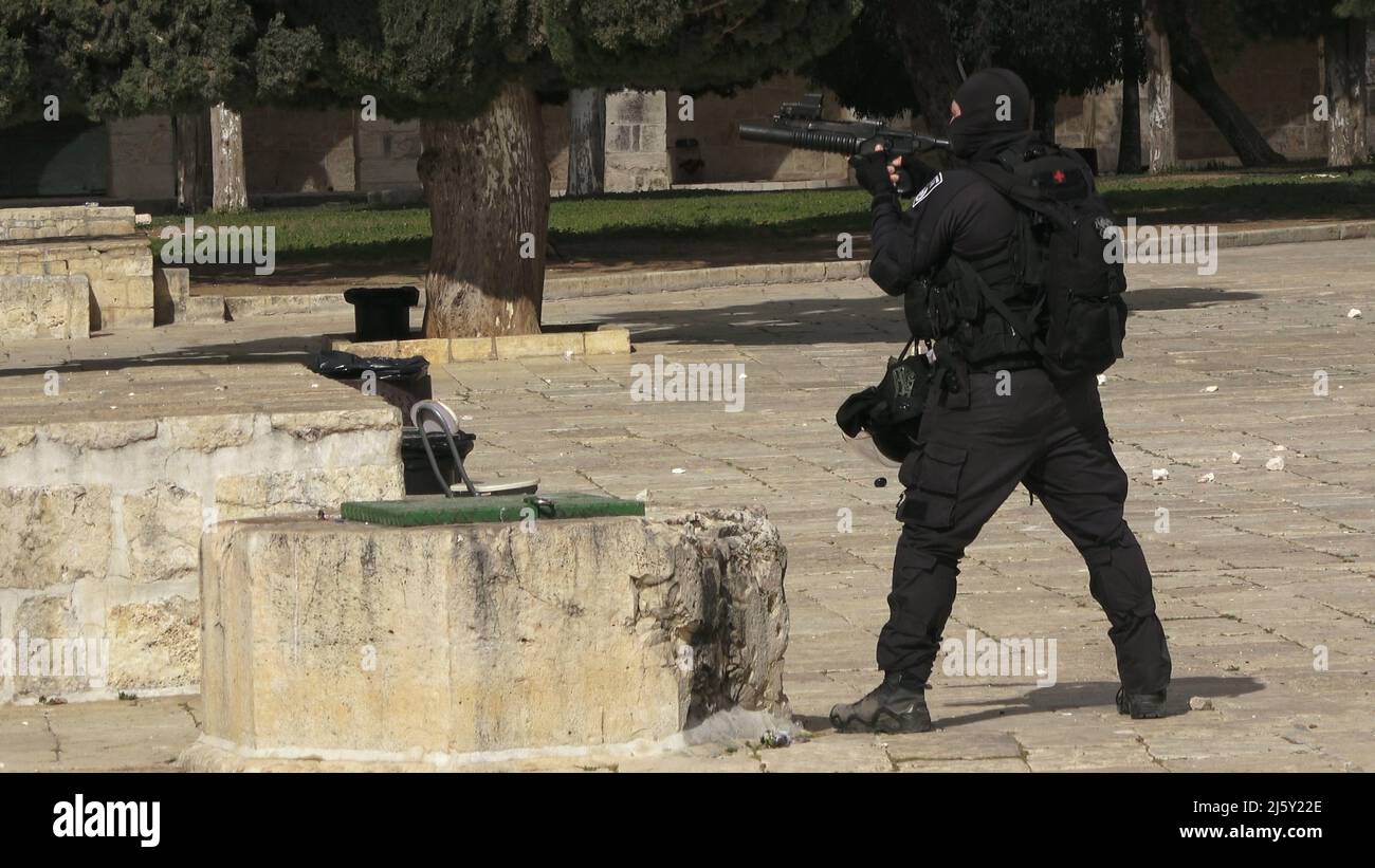 An Israeli policeman fires rubber-coated bullets at Palestinians barricading themselves inside Al-Aqsa Mosque and throwing stones at the police and a group of religious Jews visiting the Temple Mount known to Muslims as the Haram esh-Sharif (Noble Sanctuary) during the Jewish Pesach (Passover) holiday in the old city on April 20, 2022 in Jerusalem, Israel. Jews, Christians and Muslims celebrate this year's Passover, Easter and Ramadan in the same week which caused tension between Palestinians and Israelis specially in Jerusalem Stock Photo
