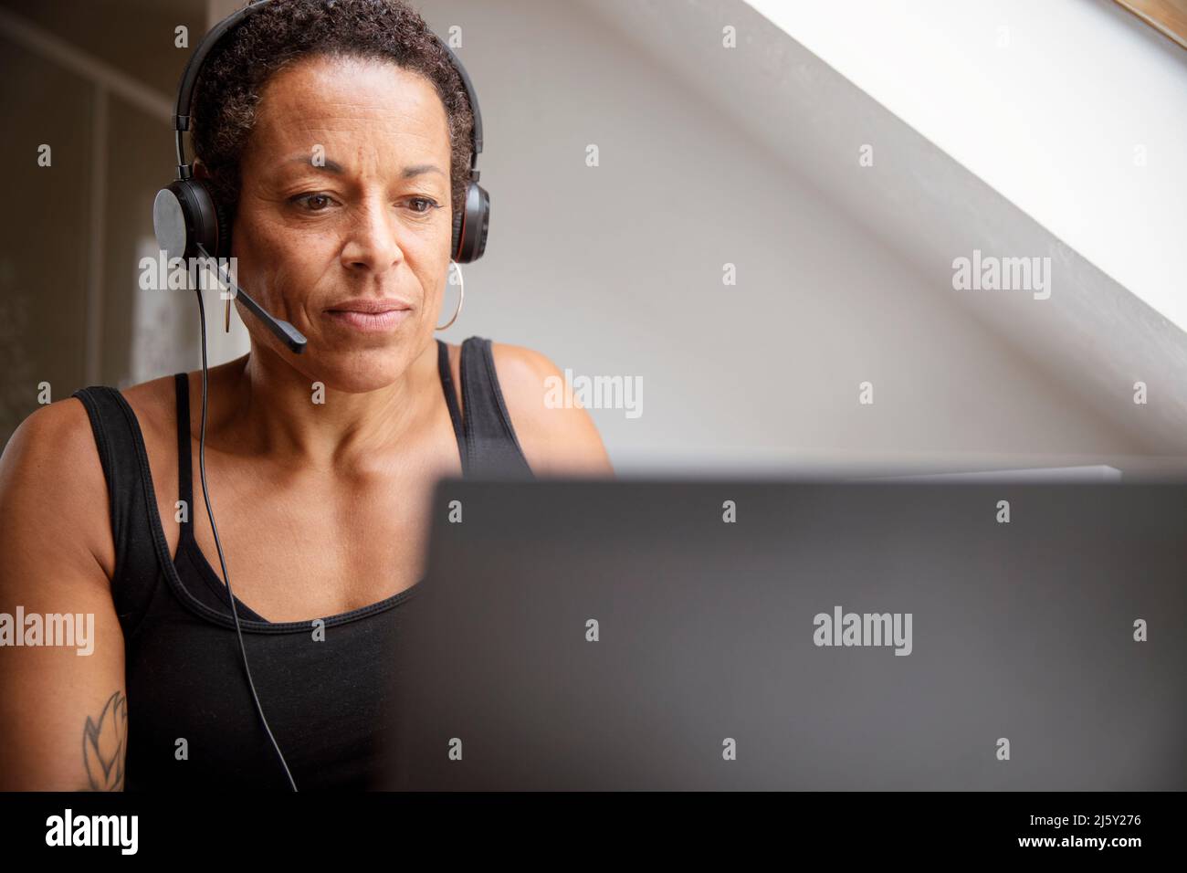 Mature woman in headset working from home at laptop Stock Photo