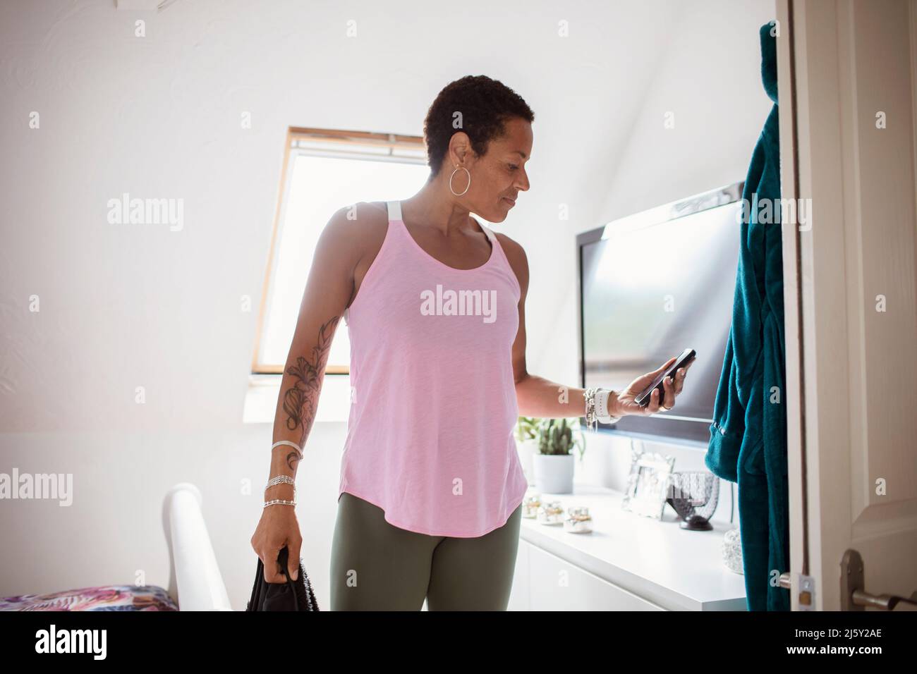 Woman with tattoos in athleisure wear using smart phone Stock Photo