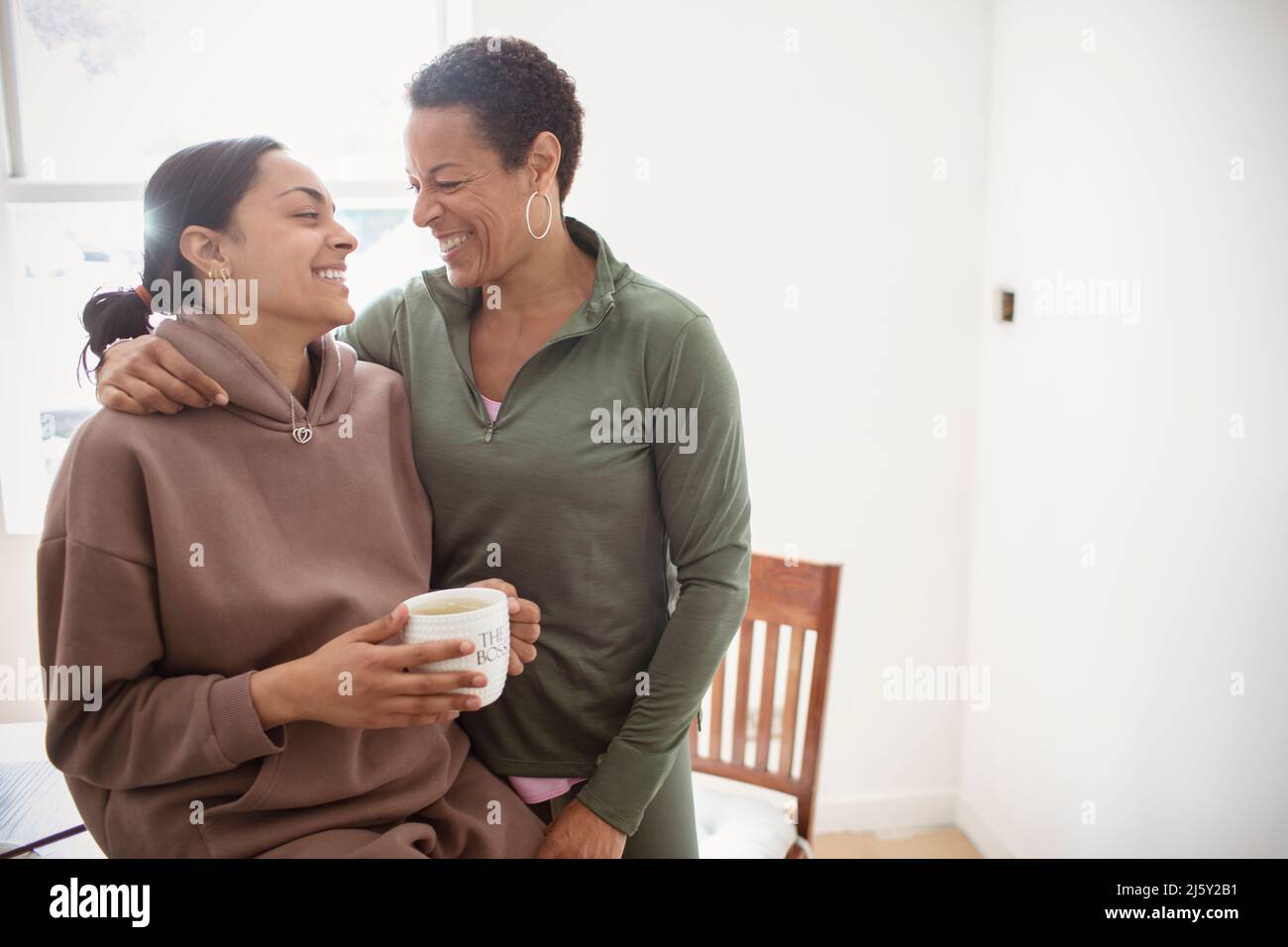 Happy mother and young adult daughter hugging at home Stock Photo