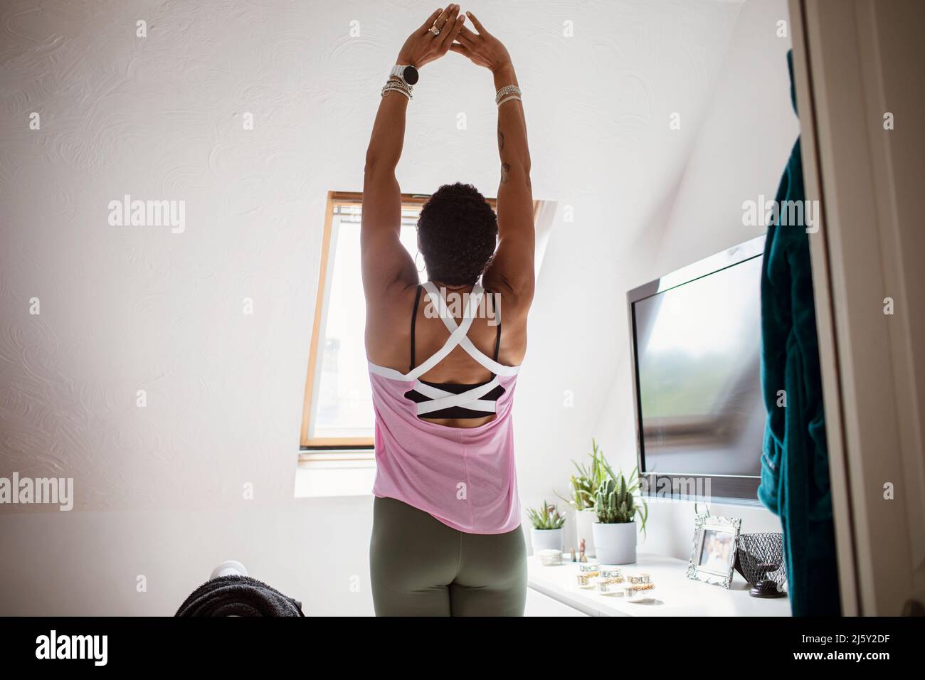 Woman exercising with arms raised at home Stock Photo