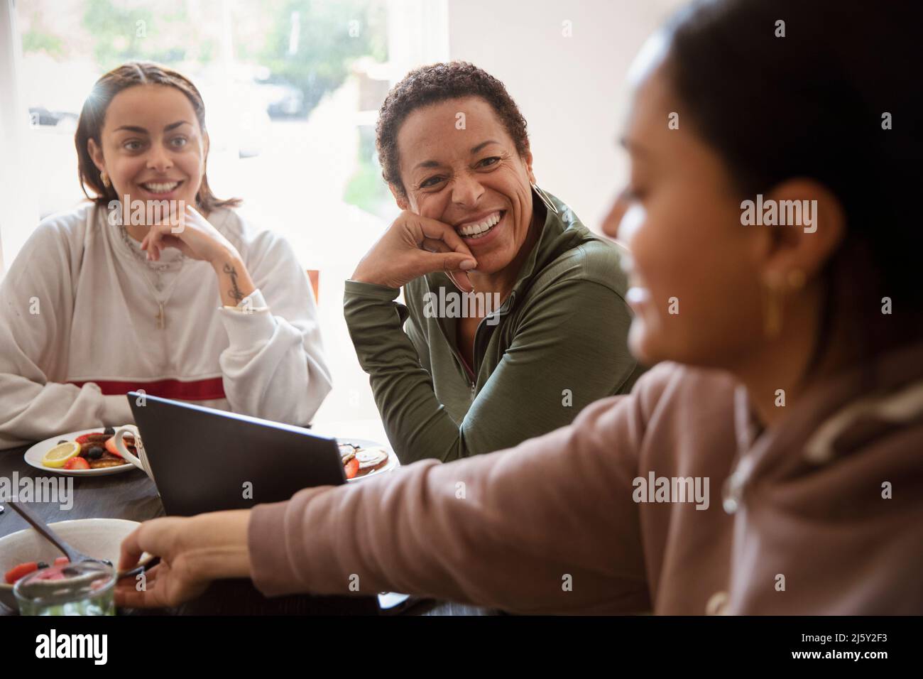 Happy mother and young adult daughters talking at home Stock Photo