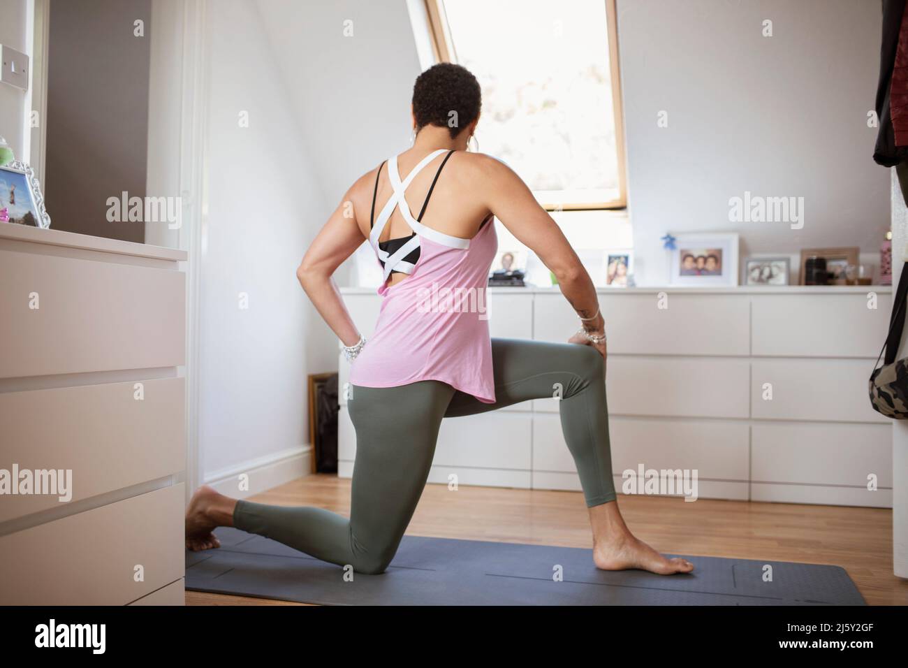 Woman exercising, practicing yoga twist on mat at home Stock Photo