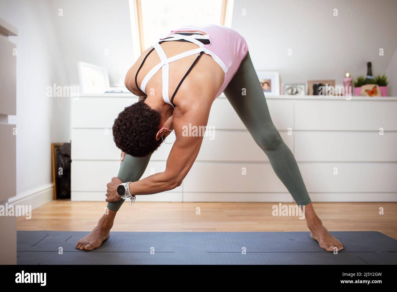 Woman exercising, stretching on yoga mat at home Stock Photo