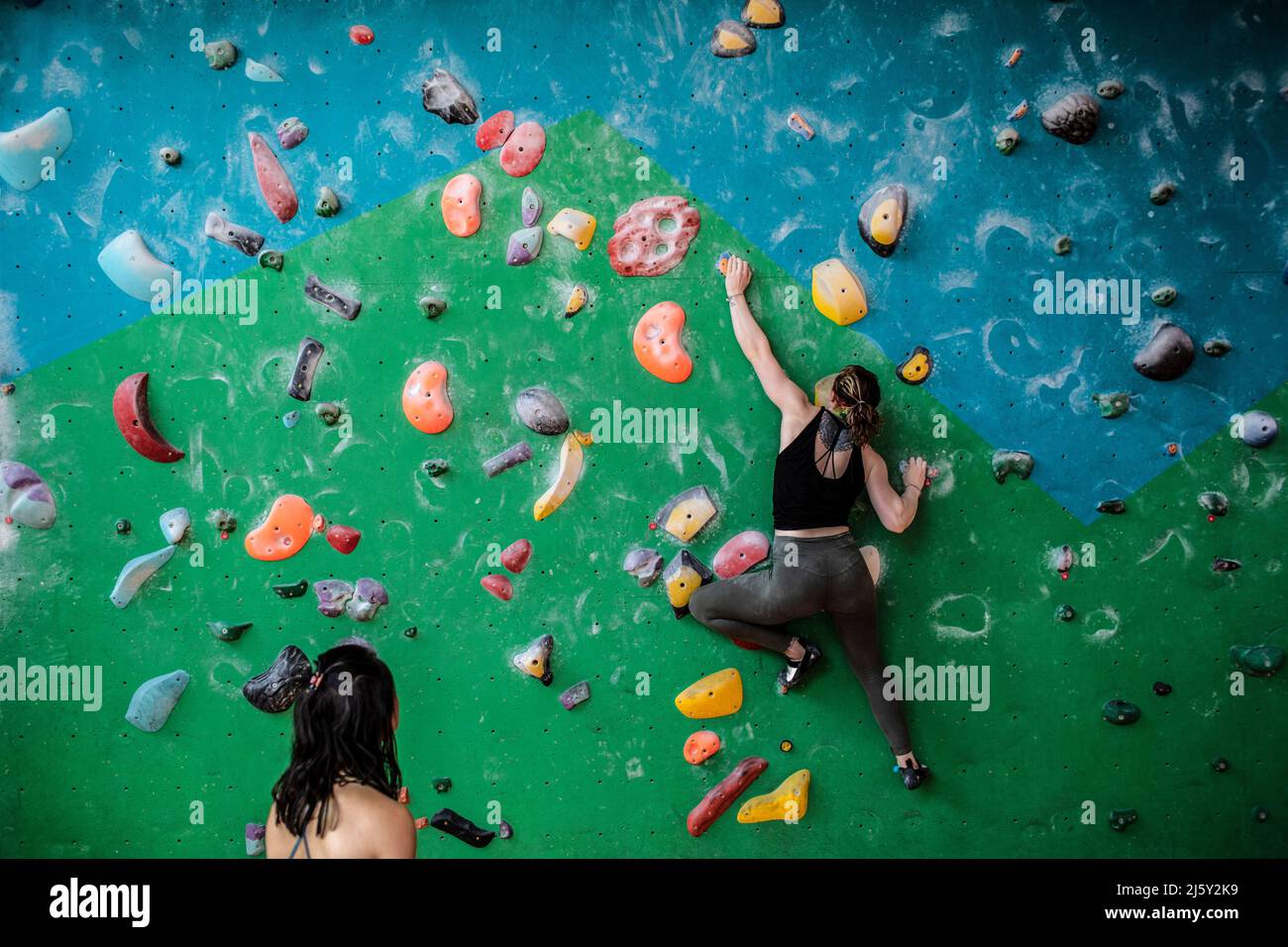 Woman hanging from rock climbing wall Stock Photo