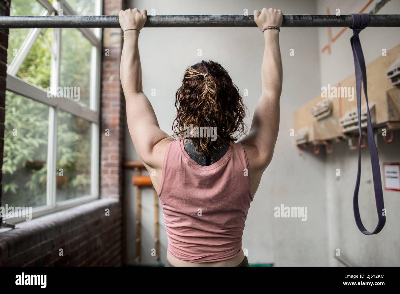 Muscular young woman working out at bar in gym Stock Photo